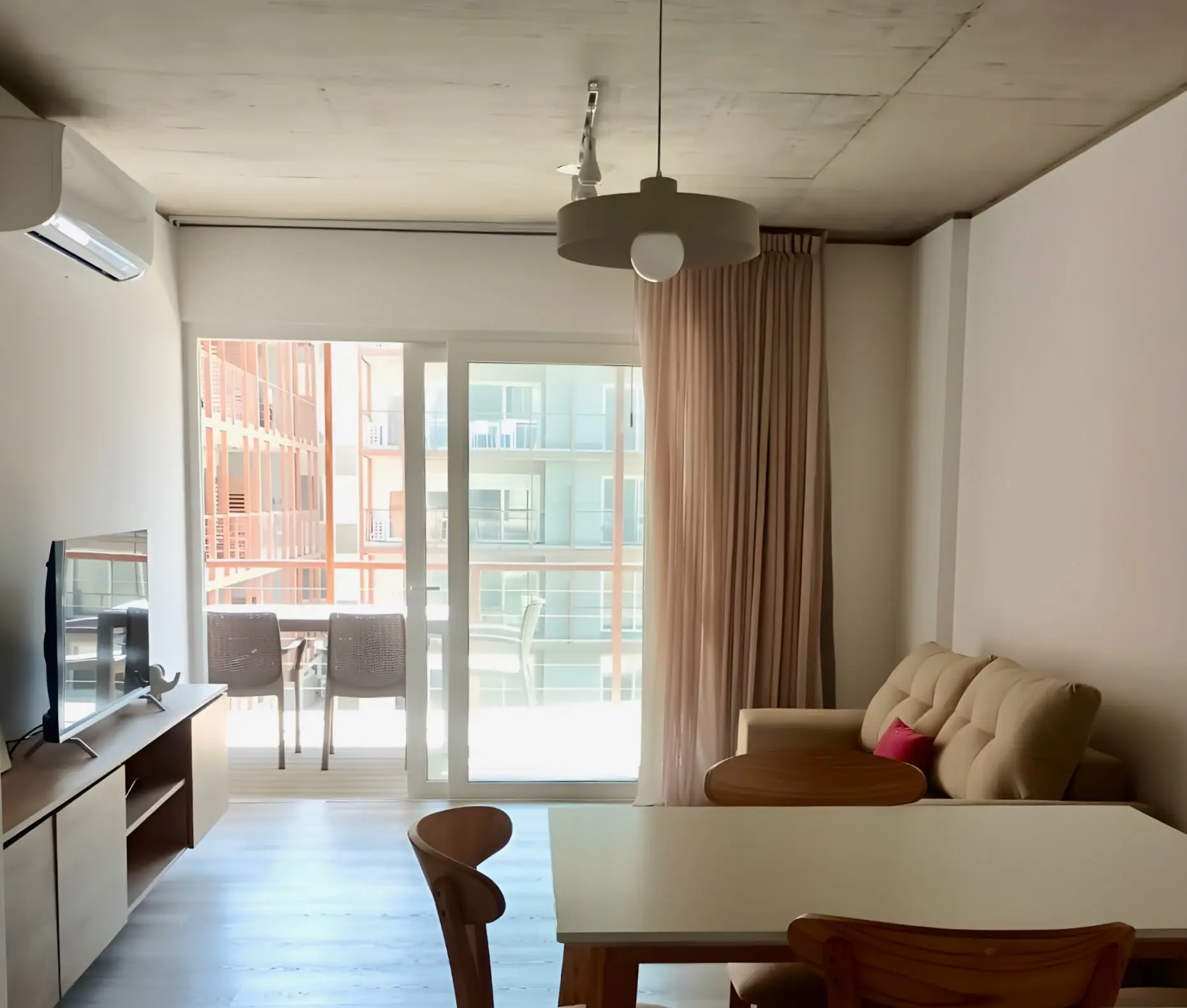 Living comedor con sofá, mesa y ventanal corredizo al balcón