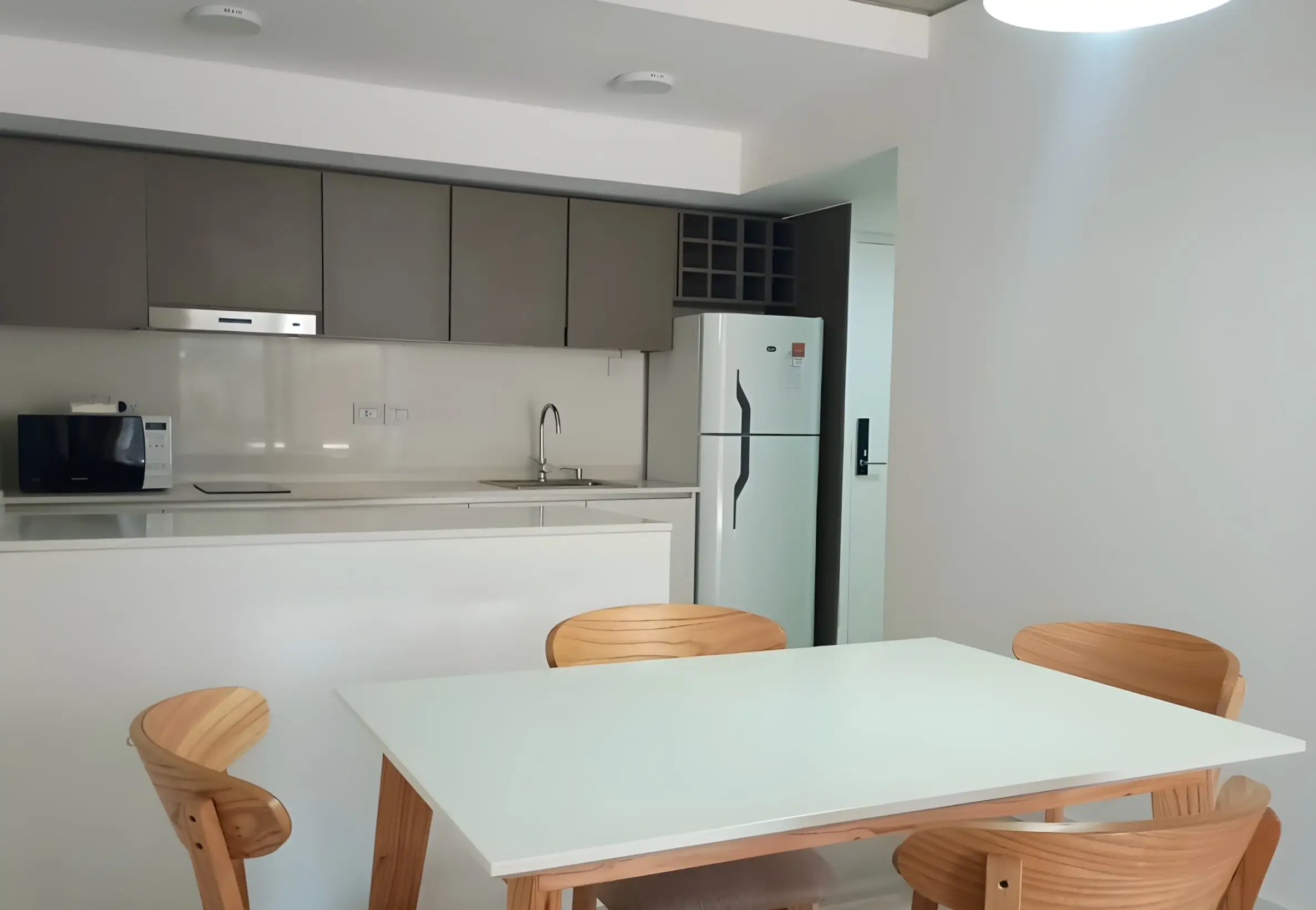 Cocina integrada con heladera con freezer, anafe y mesa de cuatro