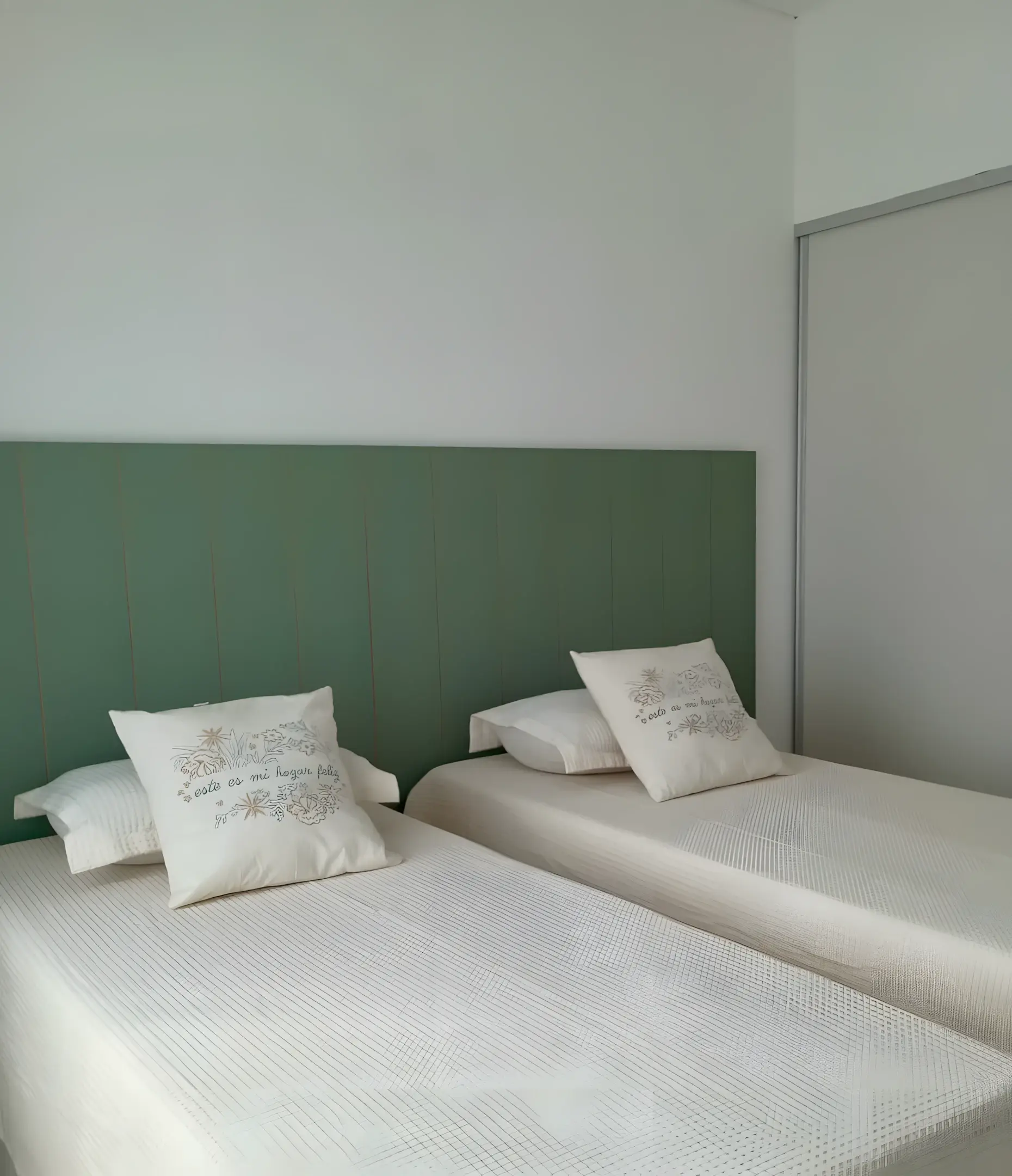 Dormitorio de dos camas con respaldo verde