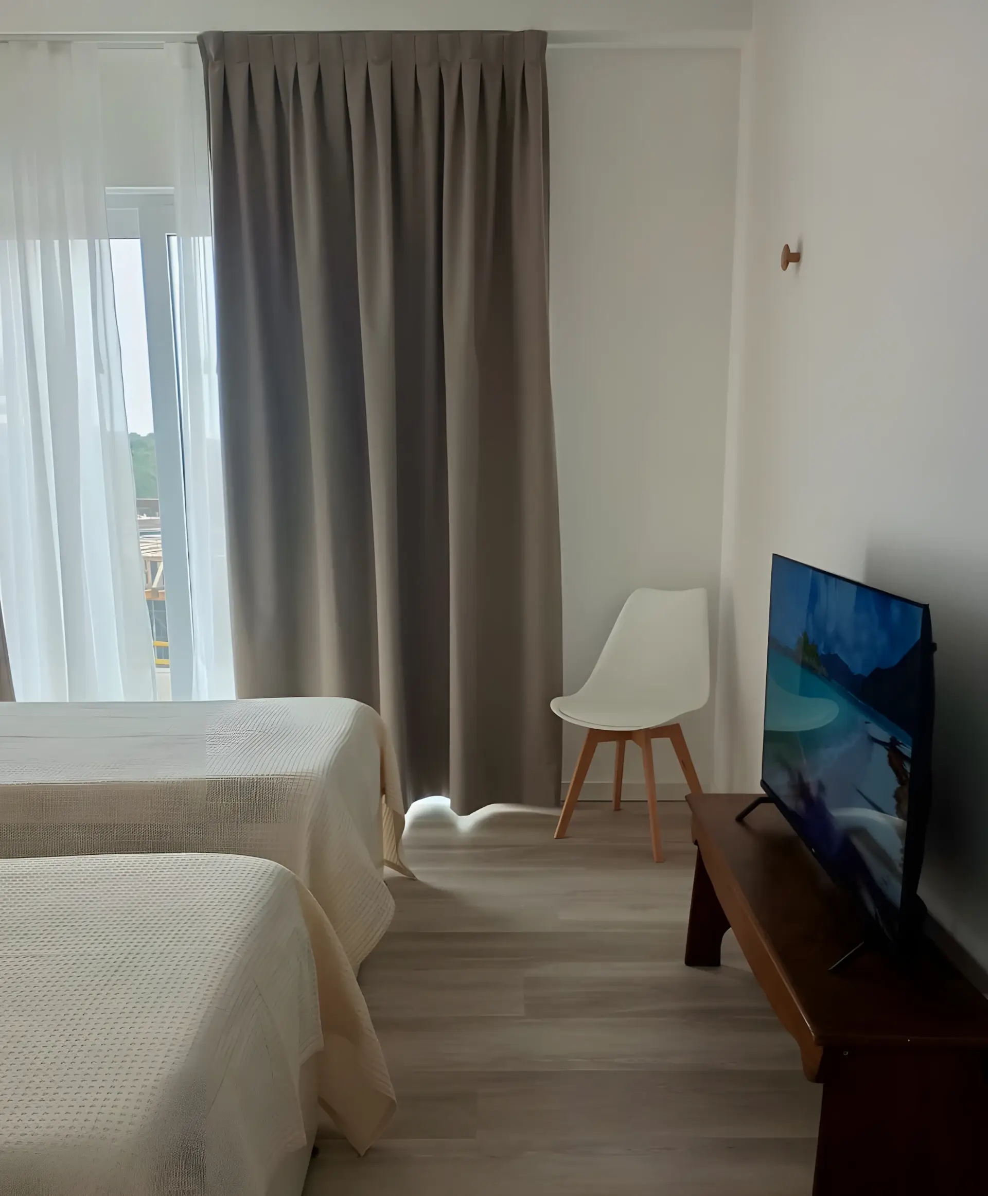 Dormitorio con televisor y silla junto al ventanal